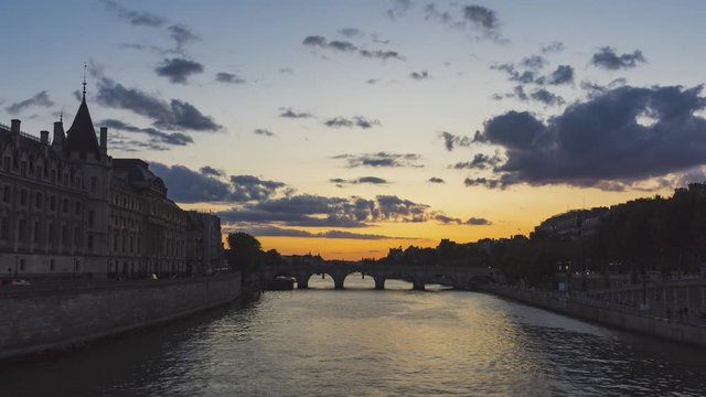 Sunset over Seine River and Conciergerie - Paris. Timelapse with boat traffic during Golden and Blue hours with illuminated bridges and monuments.