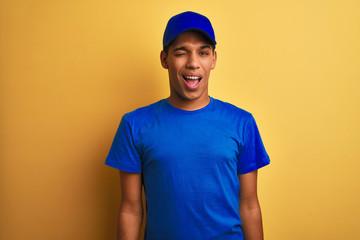 Young handsome arab delivery man standing over isolated yellow background winking looking at the...