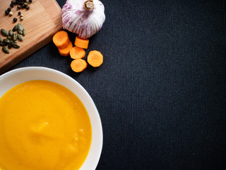 Fresh vegetable soup made with pumpkin and carrots in a dark background