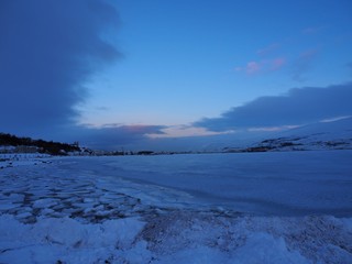 winter landscape with blue sky and clouds and a frozen lake in Iceland