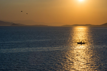 Fishermen boat at sunset in the Mediterranean Sea, near Aegina island, Saronic gulf, Greece.