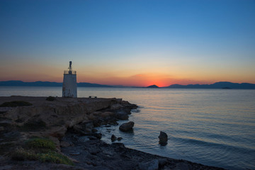 Fototapeta na wymiar Old small lighthouse of the Aegina island, Saronic gulf, Greece, at sunset.