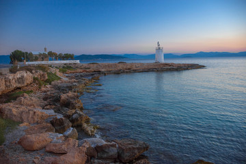 Fototapeta premium Old small lighthouse of the Aegina island, Saronic gulf, Greece, at sunset.