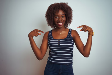 Young african afro woman wearing striped t-shirt standing over isolated white background looking...