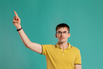 Fototapeta premium Handsome guy in a yellow casual t-shirt is posing over a blue background.
