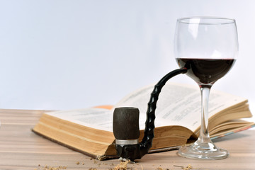 pipe, red wine, old book on the table
