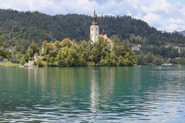Lake Bled Slovenia. Beautiful mountain lake in summer with small Church on an island with castle on cliff and european alps in the background.
