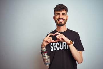 Young safeguard man with tattoo wering security uniform over isolated white background smiling in...