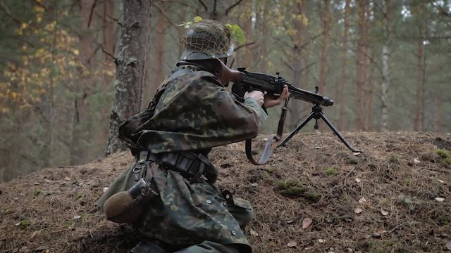 Historical Reconstruction Of The Second World War. A fascist sniper soldier in a trench with a machine gun takes aim to kill the enemy