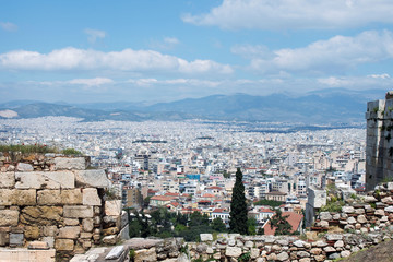 Ancient Greek ruins, ruins amidst lush green grass. Acropolis, Athens, Greece. Beautiful view of the capital of Greece - Athens from the slopes of the Acropolis on a hot sunny day.