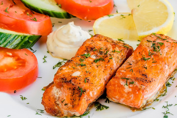 two large pieces of grilled salmon with lemon, white plate, top view macro