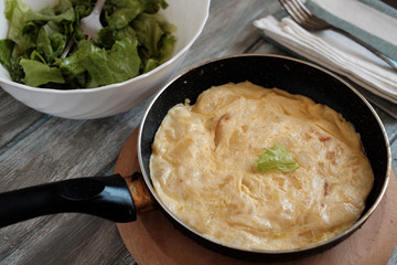 Spanish omelet in the pan and lettuce salad and onion