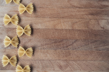 Fototapeta premium Farfalle on a wooden background. Place for text. Texture wood with notches