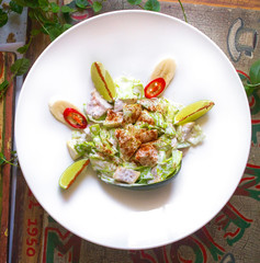 White Restaurant Plate of Caesar Salad with Chicken, Homemade Anchovies Sauces, Croutons, Tomatoes, Greens. Beautiful Delicacy Cesar Salat on Natural Dark Stone and Leaves Background
