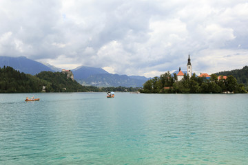 Naklejka premium Lake Bled Slovenia. Beautiful mountain lake in summer with small Church on an island with castle on cliff and european alps in the background.