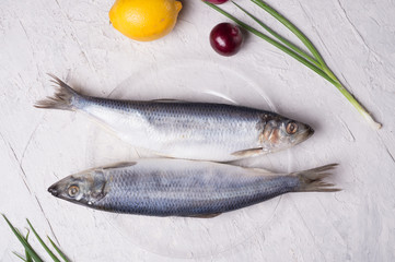 salted whole herring  on a transporant plate with defferent onions and seasonings. served in Scandinavian style. Typical cooking fish in Scandinavian countries.