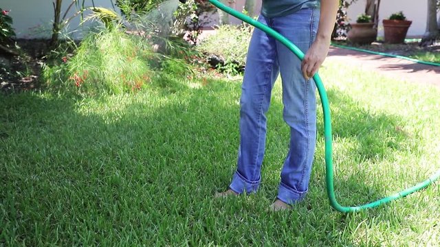 Woman watering a lawn from a hose