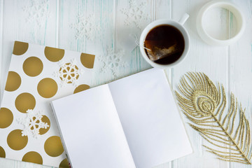Sample layout of New Year's greetings with snowflakes, open notebook, cup of tea on a light wooden background. Frame for text greetings for Christmas. Blog post publication, email newsletter template