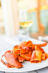 Pasta with spiny lobster and tomato sauce. Seafood lunch at the restaurant and a glass of white wine. Bluerade and selective focus on the photo.