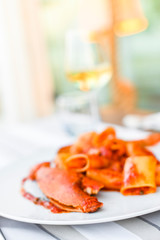 Pasta with spiny lobster and tomato sauce. Seafood lunch at the restaurant and a glass of white wine. Bluerade and selective focus on the photo.