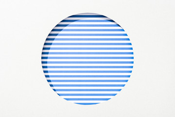 cut out round hole in white paper on blue and white striped background