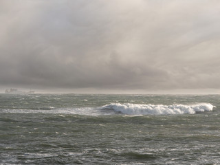 Ocean's waves, Dramatic cloudy sky, Ship silhouette on the horizon.
