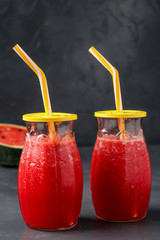 Smoothies with watermelon in jars on a dark background, vertical orientation