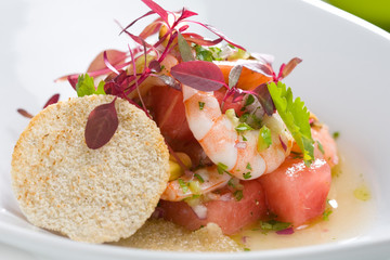 Close-up shrimp salad with watermelon, decorated with edible flowers.