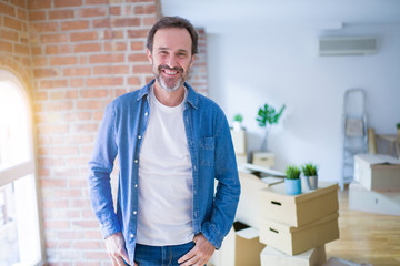 Fototapeta premium Middle age senior man moving to a new house packing cardboard boxes with a happy and cool smile on face. Lucky person.