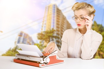 Young secretary with red phone and typing machine