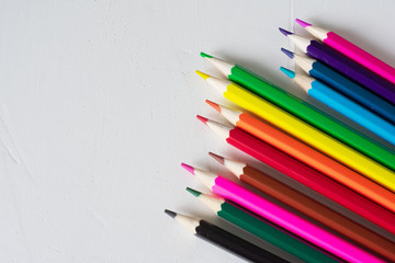 Obraz premium Many colored pencils lie on a white background. Copy spase. The concept of back to school, the educational process, study at school, drawing