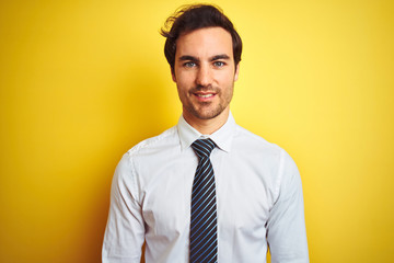 Young handsome businessman wearing elegant shirt and tie over isolated yellow background with a happy and cool smile on face. Lucky person.