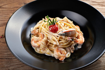 Spagetti with shrimp on a black plate (Fettuccine)