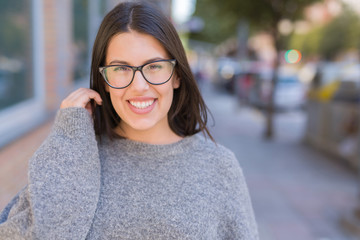 Young beautiful woman wearing glasses smiling confident walking on the street at the city town