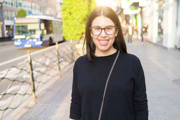 Beautiful young brunette woman smiling excited walking down the city streets, happy and confident expression standing outdoors at the town