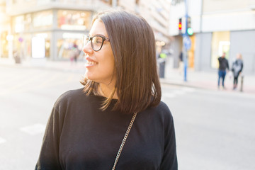 Beautiful young brunette woman smiling excited walking down the city streets, happy and confident expression standing outdoors at the town