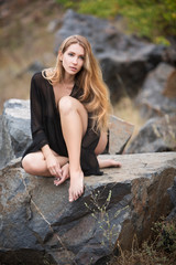 beautiful young woman with chic bushy hair sits on a stone