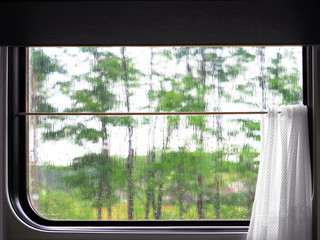 Window of the  train, railroad. Rain outside the window. Smudges of water on the glass, curtains