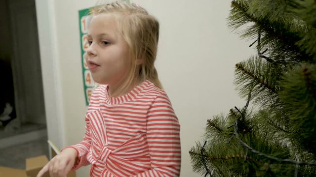 Happy family decorating a Christmas tree with boubles in the living-room