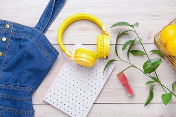 Modern headphones, female clothes, notebook and lemons on wooden background