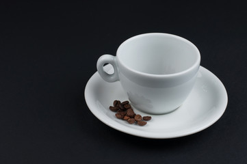 White cup of coffee and coffee beans isolated on black background
