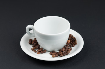 White cup of coffee and coffee beans isolated on black background