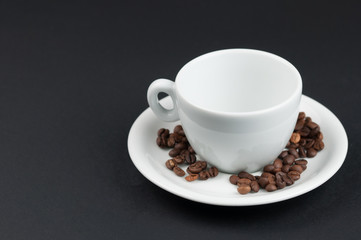 White cup of coffee and coffee beans isolated on black background
