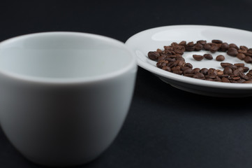 White cup of coffee and coffee beans isolated on black background