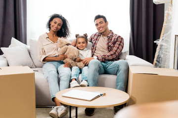 full length view of african american family sitting on sofa and looking at camera