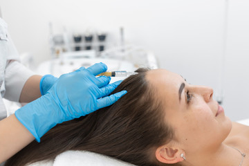 Beautician injections for healthy hair growth. Mesotherapy of the scalp. A young girl is undergoing a course of spa treatments in the office of a beautician. Moisturizing, cleaning and facial 