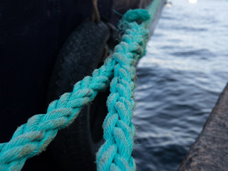 Bright green thick ropes tied tightly for a  secure harbor docking. The boat is docked in the Swedish capital Stockholm.