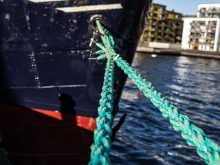 Bright green thick ropes tied tightly for a  secure harbor docking. The boat is docked in the Swedish capital Stockholm.