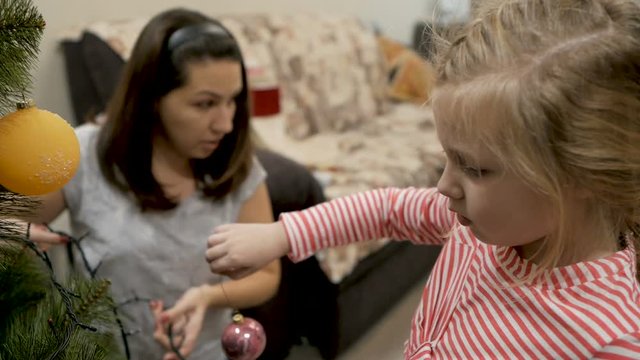 Happy family decorating a Christmas tree with boubles in the living-room