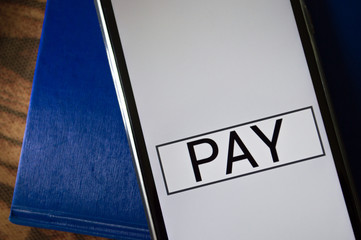 smartphone displaying generic application (app) with information PAY in screen, on table with...